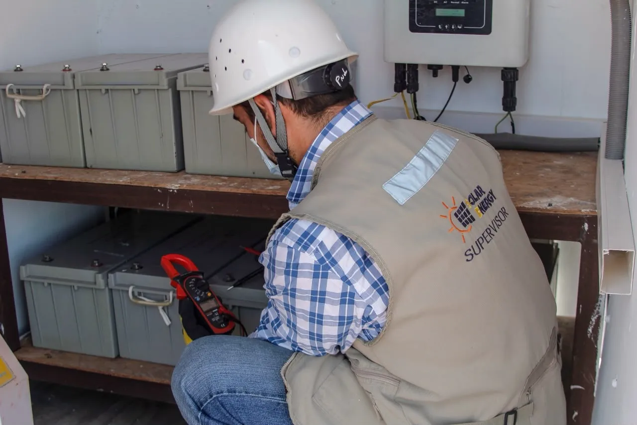 Supervisor de Solar Energy revisando las baterías y el inversor de un sistema solar